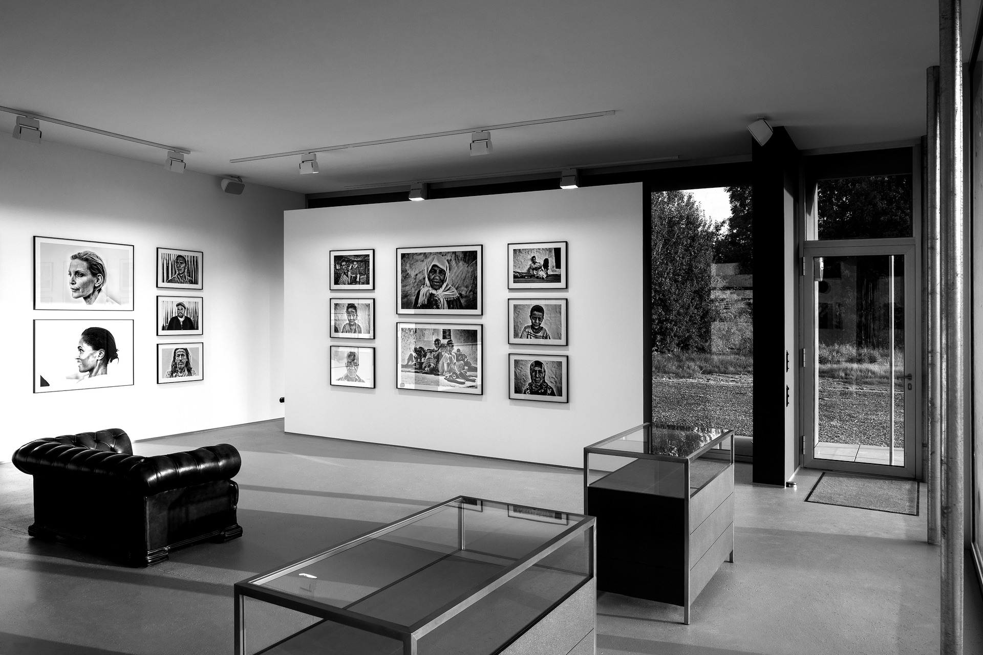 Ett elegant svartvitt galleri med porträtt på väggarna och en stilfull lädersoffa.