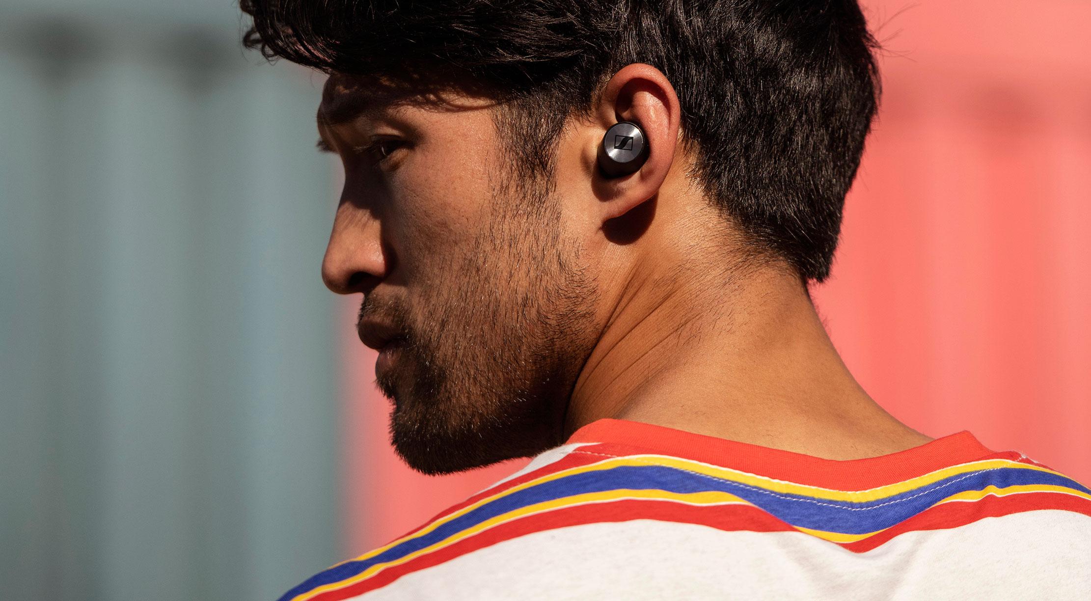 En man bär Sennheiser Momentum True Wireless hörlurar, perfekta för trådlös musikupplevelse på språng.