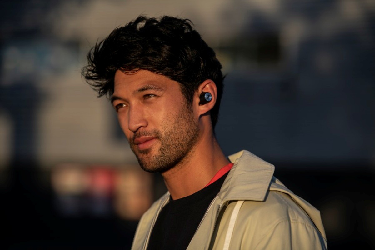 En man bär Sennheiser Momentum True Wireless-hörlurar, idealiska för musiklyssning på språng.