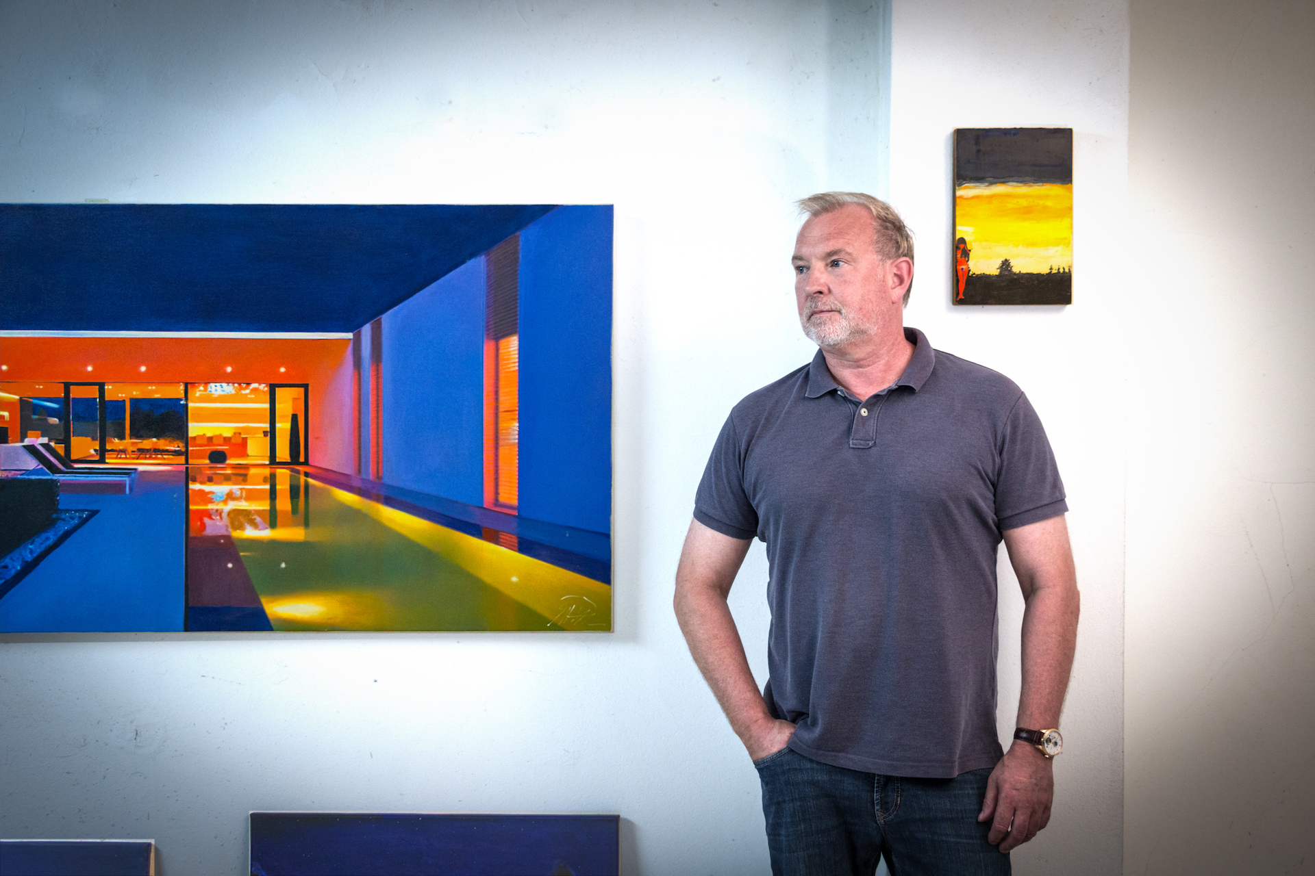 Matthias Poltrock framför sina färgstarka målningar som visar modern arkitektur och stämningsfulla landskap.